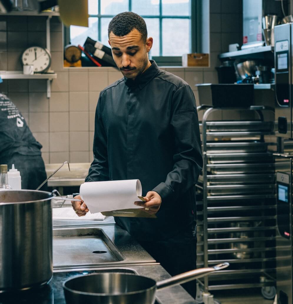 Kock i hybridskjorta läser recept i köket.